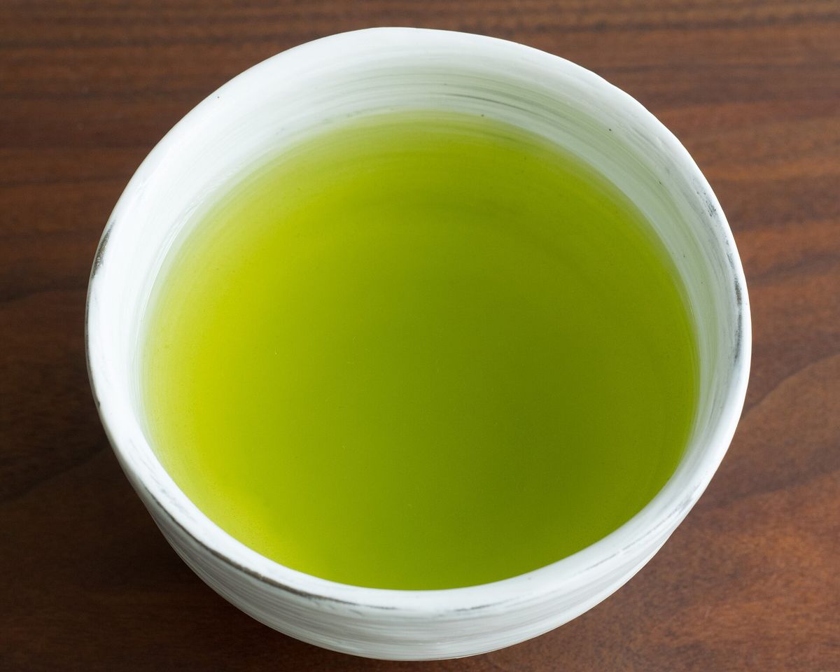 Eine weiße Teeschale mit hellgrünem japanischem Sencha-Tee
